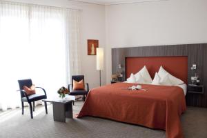 a hotel room with a large bed and two chairs at Hotel Linner in Erding