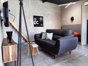 a living room with a black couch and a tv at Begonias Loft cerca del Auditorio Telmex! in Guadalajara