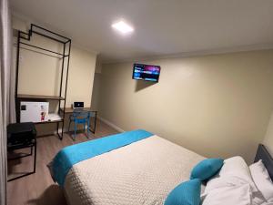 a bedroom with a bed and a tv on the wall at Hotel Suntuoso in Brasilia