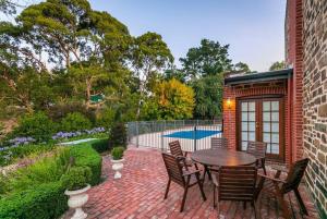 a brick patio with a table and chairs and a pool at Hahndorf Luxury Retreat in Hahndorf