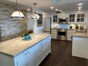 a kitchen with white cabinets and marble counter tops at Kaanapali Royal Golf Retreat in Lahaina