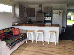 a kitchen with a counter and two bar stools at Black Beauty - Double Family Lake House for 12 with a NEW SPA & Pets in Mangakino