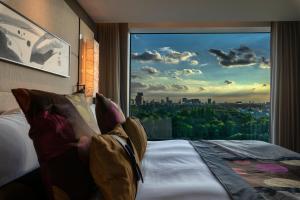 a person laying on a bed looking out a window at Hotel New Otani Tokyo EXECUTIVE HOUSE ZEN in Tokyo
