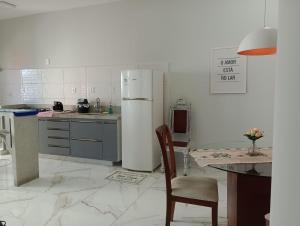 a kitchen with a refrigerator and a table and a chair at Cantinho FW in Ubatuba