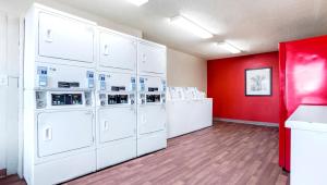 Home 1 Suites Extended Stay في مونتغومري: غرفة غسيل مع غسالات بيضاء وجدار احمر