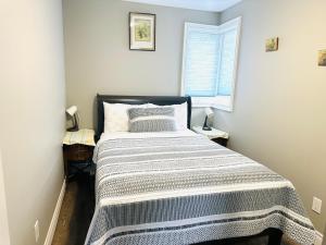 Un dormitorio con una cama con una manta a rayas. en Cozy 3-bedroom farmhouse in wine-country en Niagara on the Lake
