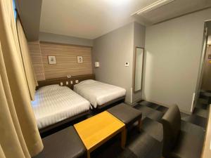 a room with two beds and a bench in it at Smile Hotel Nagano in Nagano