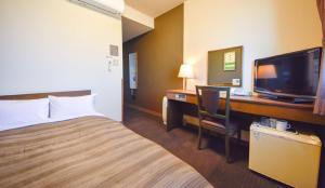 um quarto de hotel com uma cama e uma secretária com uma televisão em Hotel Route-Inn Kakamigahara em Kakamigahara