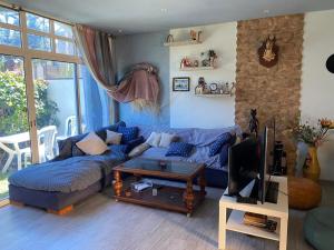 a living room with a blue couch and a tv at Maison du bonheur in El Harhoura
