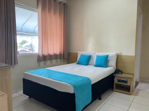 a bedroom with a bed with blue pillows and a window at Star Hotel in Taguatinga