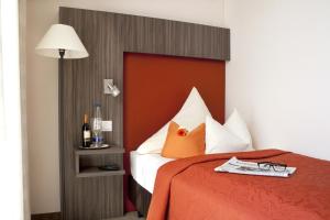 a bedroom with a bed with a red head board at Hotel Linner in Erding