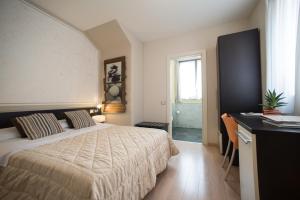 a bedroom with a bed and a desk and a window at Berghotel in Bergamo