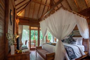 1 dormitorio con cama con dosel en una casa en The Compass Rose Ubud, en Ubud