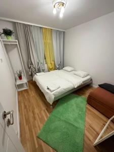 Dormitorio pequeño con cama y alfombra verde en green apartment 38 berceni, en Bucarest