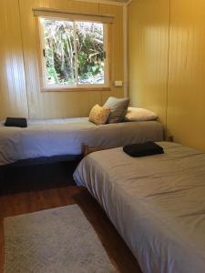 2 camas en una habitación con ventana en CABAÑAS RÜPÜ PUYUHUAPI, en Puerto Puyuhuapi