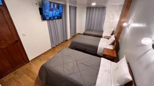 Habitación pequeña con 2 camas y TV de pantalla plana. en QUECHUA´S HOUSE Hostal & Coffee en Machu Picchu