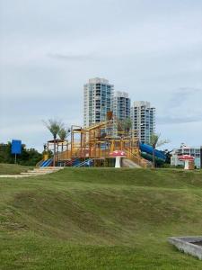 einen Spielplatz in einem Park mit Gebäuden im Hintergrund in der Unterkunft Lujoso y Familiar Apartamento de Playa y Golf en San Carlos Panamá in San Carlos