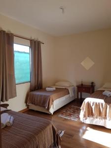 a bedroom with two beds and a window at Abrigo Serafina#cama&café in Itamonte