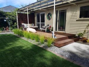 a cat laying on a wooden deck in front of a house at Rainbow Gate Cottage in Napier