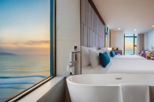 a bathroom with two beds and a bathtub in a room at Peninsula Hotel Danang in Danang