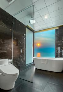 a bathroom with a tub and a toilet and a window at Peninsula Hotel Danang in Danang