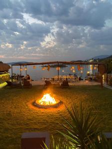 a fire pit in a field with a lake in the background at Erythros Hotel in Çeşme
