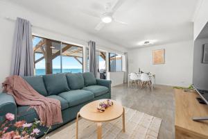 a living room with a blue couch and a table at Sea Breeze Two Bedroom Apartment in Redcliffe