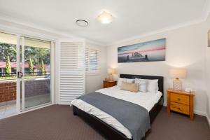 a bedroom with a large bed and a balcony at Government Rd 77 Shoal Bay in Shoal Bay