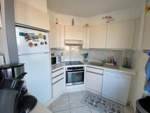 a kitchen with white cabinets and a white refrigerator at T3 Moderne 6p au bord de la mer, Le Barcarès, parking et terrasse - FR-1-81-593 in Le Barcarès