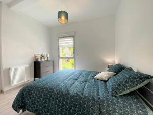 a bedroom with a bed with a blue comforter and a window at Appartement neuf avec balcon, proche du port de Perros-Guirec - FR-1-368-392 in Perros-Guirec