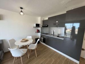 eine Küche mit einem Tisch und Stühlen sowie eine Küche mit einem Waschbecken in der Unterkunft Appartement Valras-Plage, 2 pièces, 4 personnes - FR-1-701-66 in Valras-Plage