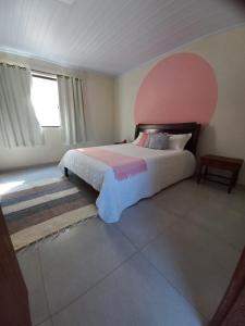 a bedroom with a large bed with a pink headboard at Chalé Penedo Charmosa in Penedo