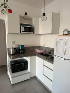 a kitchen with white cabinets and a microwave and a sink at Departamento en Corrientes in Corrientes