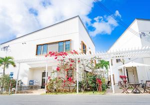 uma casa branca com flores à frente em Hotel California Miyakojima Resort em Ilhas Miyako