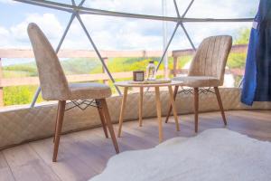 two chairs and a table in front of a window at Sanctum Glamping in Jupâneşti