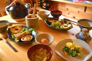 einen Holztisch mit Teller mit Lebensmitteln und Schüsseln in der Unterkunft 玄か~sizuka~ 