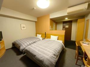 a hotel room with two beds and a desk at Hotel Route-Inn Aizuwakamatsu in Aizuwakamatsu