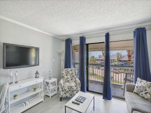a living room with a tv and a chair and a balcony at Casa Del Mar 174-sea U Soon in Galveston