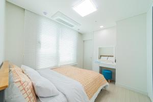 a white bedroom with a bed and a desk at Again in Daejeon