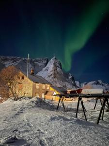 una casa en la nieve con la aurora en el cielo en Det Gamle Hotellet Guesthouse en Reine