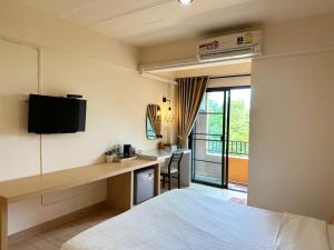 Habitación de hotel con cama y escritorio con TV. en I-Home Residence and Hotel en Pluak Daeng