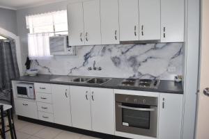 a kitchen with white cabinets and marble counter tops at Crystal Waters 7 in Bargara