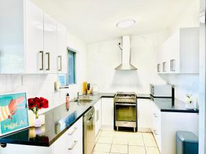 una cocina con armarios blancos y encimeras negras en Grabber- Three bedroom charm in Alice Springs en Alice Springs