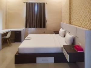 a bedroom with a bed with a desk and a red phone at RedDoorz Syariah near Sultan Syarif Kasim II Airport in Pekanbaru