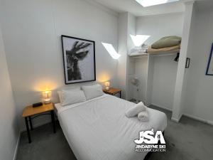 sypialnia z dużym białym łóżkiem i dwoma stołami w obiekcie Razorback 3 w mieście Jindabyne