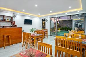un restaurante con mesas y sillas de madera y un bar en Tomorrow Oasis Boutique Villa Hoi An, en Hoi An