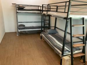 a room with three bunk beds and a wooden floor at Guesthouse Comfort Place in Buan