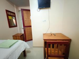 a room with a bed and a table and a television at Balqies Homestay Syariah Makassar Mitra RedDoorz in Makassar