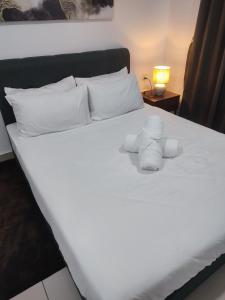a white bed with white towels on top of it at MAI Desaru Utama Residence in Bandar Penawar