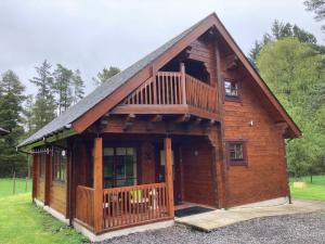 a log cabin with a balcony and a deck at Norwegian Log Cabin The Roe Deer -sauna & hot tub in Keith